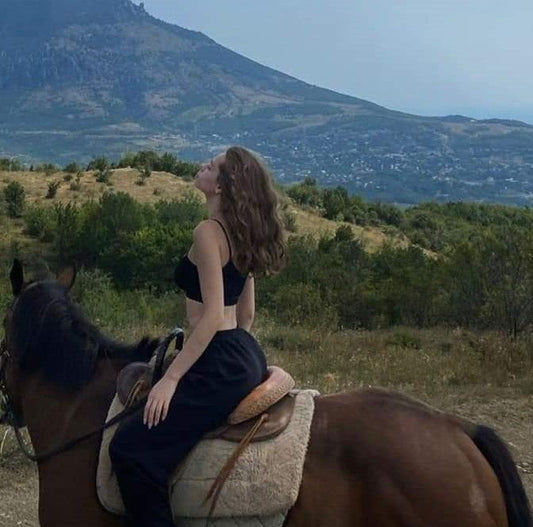 Mujer disfrutando de un paseo a caballo en la naturaleza con vistas a la montaña en Solsona, experiencia ecuestre de Hípica Cap de Costa.